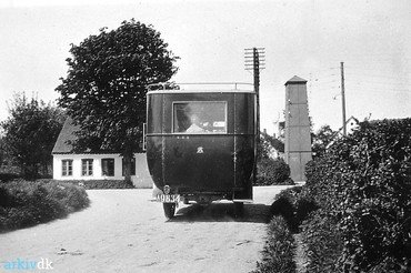 Bussen fra Tune ved udkørslen til Ved Kirken i 1920erne. Centralen med sit store træ ses til venstre, til højre transformatorstationen.