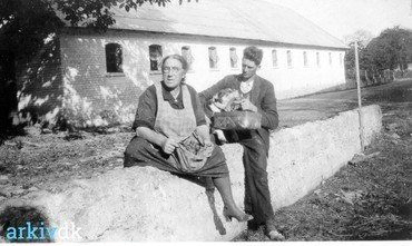 Foto fra Lysegård. Siddende foran svinehuset Holger Andersen med hund. Kvinden er ukendt. Cirka år 1930.