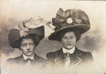 Olga (til højre) med en veninde, iført storslåede hatte-kreationer. Olga var hattemagerske eller modist og arbejdede bl.a. for Illum. Hun og hedes mand, Henry Søgård, boede på Østerbro.