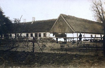 Lundbjerggaard før 1. verdenskrig. Til højre Lars Peter Poulsen med hestetrukken radrenser foran vestlængen, som måtte lade livet for det nye stuehus. indenfor gavlen var der høns, resten af længen var lo og lade. Til venstre det gamle stuehus mod nord, bemærk vippebrønden yderst til venstre.