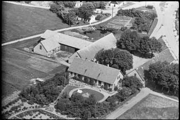 Luftfoto af Mørbjerggaard ca. 1936. Bemærk den store have og bevoksningen, som trods fældninger i 1970erne efter salget til Tage Nielsen stadig fylder godt på "Trekanten". Læg også mærke til den nye Tunevej til højre og vejene til Øde Hastrup og til Ørnemosegaard og Søndergaard øverst til venstre.